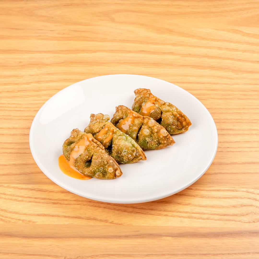 Plate of crispy vegetarian gyoza, showcasing golden-brown dumplings filled with vegetables, covered in sauce at Kinton Ramen.